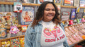 Model wearing white Poligear Grow a Pair graphic tee in a retro candy shop