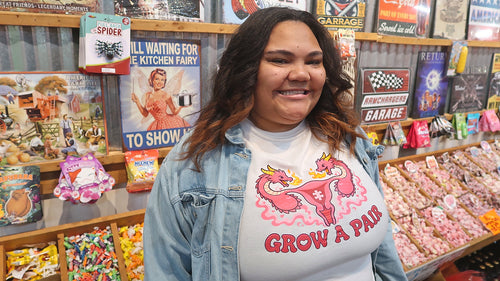 Model wearing white Poligear Grow a Pair graphic tee in a retro candy shop